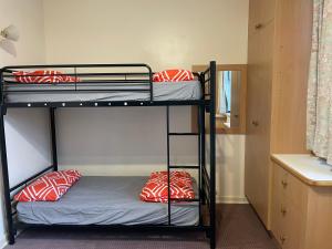 two bunk beds in a dorm room with red and white pillows at sj hostel in Legana