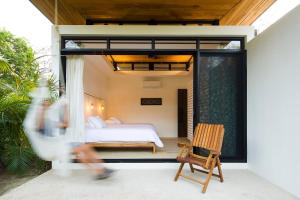 a woman walking past a bedroom in a house at Nalu Nosara Pool Villa Jardin in Nosara