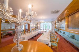 una sala da pranzo con tavoli, sedie e lampadario a braccio di Hotel Three Lilies inkl Aquaforum a Františkovy Lázně