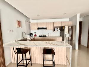 una cocina con una isla grande con 2 taburetes en Departamento Boca del Rio Costa de Oro, 