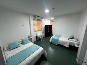 a hotel room with two beds and a window at La Isla Del Descanso in Puerto Villamil