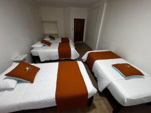 a group of three beds in a room at La Isla Del Descanso in Puerto Villamil