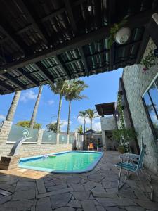 a swimming pool with a chair and palm trees at Suíte Toy Story - Pousasa Castelo do Luar in Penha