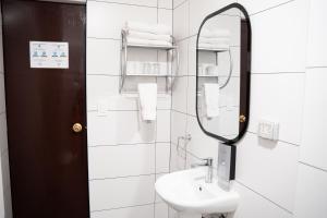 Un baño blanco con lavabo y espejo. en Hotel Cusco Plaza Saphi, en Cusco