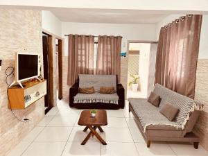 a living room with a couch and a tv at Casa em Bertioga com piscina aquecida Sitio família ROCHA in Bertioga