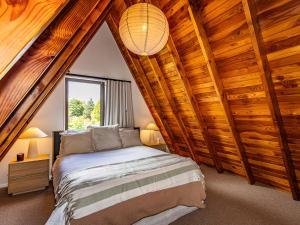 a bedroom with a bed in a room with wooden ceilings at Peaks and Pines Chalet - Ohakune Holiday Home in Ohakune