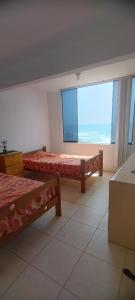een slaapkamer met twee bedden en een groot raam bij Departamento en Playa Pulpos - 2 habitaciones - Piscina compartida in Arica
