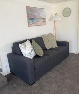 a blue couch in a living room with a clock at Turners Beach Holiday Cabin in Turners Beach +1 photo
