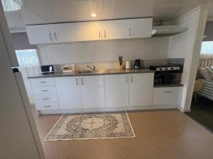a kitchen with white cabinets and a sink at Turners Beach Holiday Cabin in Turners Beach
