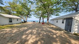 a dirt road next to a white building and trees at Northern Lights Beach Resort in Au Sable