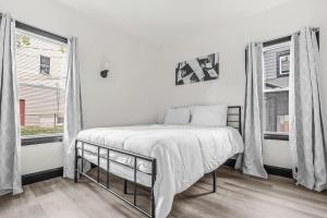 a white bedroom with a bed and two windows at Charming 4BR Niagara Apartment Great Location in Niagara Falls
