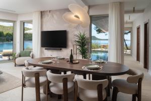 a living room with a table and chairs and a television at Luxury villa Zara, first row to the sea! in Kali