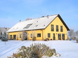 a yellow house with a snow covered yard at Carol's Country-House in Seehof