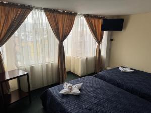 a hotel room with two beds and a window at Hotel Inti Raymi in Pasto