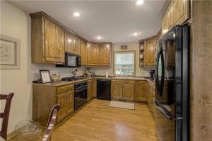 a kitchen with wooden cabinets and a black refrigerator at The American Carriage House in Liberty +4 photos