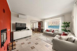 a living room with a couch and a flat screen tv at Villa Melody by Aura Luxury Collection in Molino Nuovo