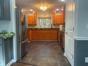 a kitchen with wooden cabinets and a tile floor at Quiet Forest Vacation home on a Private Road with Spacious Patios, Fire pit, Pet friendly and a Private pool in Tullahoma