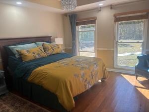 a bedroom with a bed with a yellow comforter and two windows at Quiet Forest Vacation home on a Private Road with Spacious Patios, Fire pit, Pet friendly and a Private pool in Tullahoma +53 photos