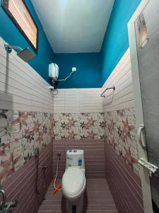 a bathroom with a toilet and a blue wall at Love Home stay in Dharmpura