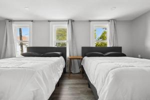 two beds in a room with two windows at 4BR Niagara Falls Home Free Parking WiFi in Niagara Falls