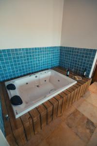 een badkamer met een bad en blauwe tegels bij Hotel Via Do Sol Eco Chalés in Trairi