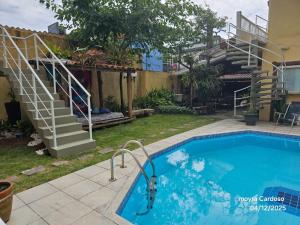 a swimming pool in a yard with a staircase at Flor de Jagube Guest House in Ubatuba