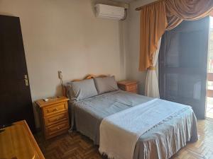 a bedroom with a bed and a dresser and a window at Casa de veraneio 2 dormitórios in Torres