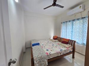een kleine slaapkamer met een bed en een plafondventilator bij Northern Aura in Bangalore +15 foto's