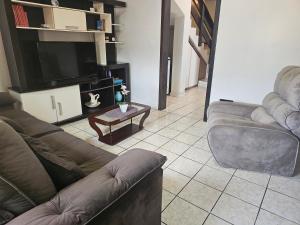 a living room with couches and a flat screen tv at Casa de veraneio 2 dormitórios in Torres