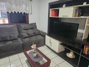 a living room with a couch and a television at Casa de veraneio 2 dormitórios in Torres +4 photos