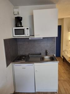 a small kitchen with a microwave and a sink at Studio meublé centre ville Paray A4 in Paray-le-Monial