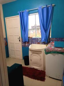 a blue bathroom with a toilet and a window at Casa temporada perto do centro in Garopaba +6 photos