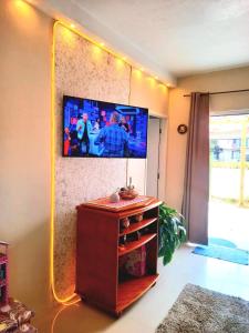 a living room with a flat screen tv on the wall at Casa temporada perto do centro in Garopaba