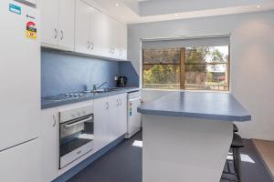 a kitchen with white cabinets and a blue counter top at Sandcastle 7 with WiFi in Tuncurry