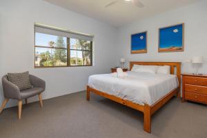 a bedroom with a bed and a chair and a window at Sandcastle 7 with WiFi in Tuncurry