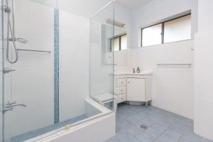 a white bathroom with a shower and a sink at Sandcastle 7 with WiFi in Tuncurry