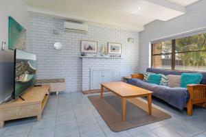 a living room with a couch and a tv at Sandcastle 7 with WiFi in Tuncurry