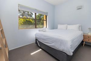 a white bedroom with a bed and a window at Sandcastle 7 with WiFi in Tuncurry +5 photos