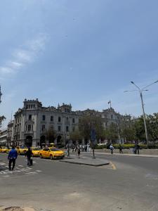 a group of people walking around a street with yellow taxis at Apartment in Lima's historic center in Lima