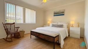 a white bedroom with a bed and a chair at Casa Bella in Lakeside
