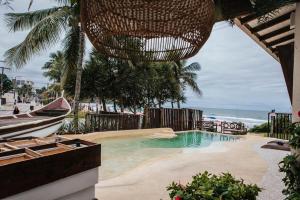 a swimming pool next to a beach with a boat at Pousada Casa Canoa - Pé na Areia & Alta Gastronomia in Guarujá