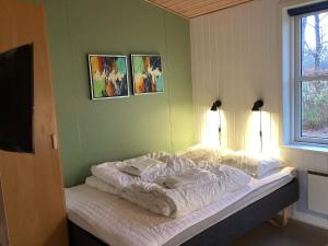 Holiday home for 2 guests, Ansager في Ansager: سرير في غرفة مع صورتين على الحائط