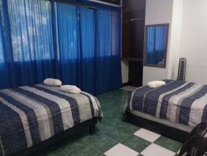 twee bedden in een kamer met blauwe gordijnen en groene bij Departamentos Arista in Oaxaca City