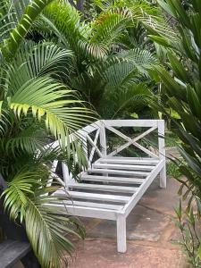 Kwa Nzeu في شاطئ دياني: مقعد أبيض يجلس أمام بعض النباتات