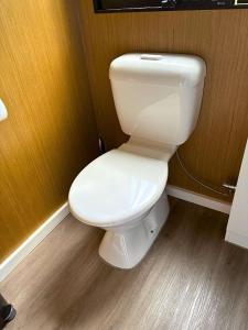a white toilet in a bathroom with a wooden wall at The Stables by Tiny Away in Palmwoods +8 photos