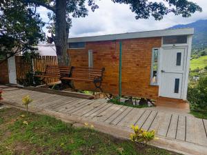 una casita con un banco en una terraza de madera en Cabaña Colibrí Silvania Cundinamarca, en Silvania