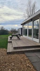 una terraza de madera con una mesa de picnic en una casa en Milan Farm Chalet cozy, en Milán