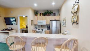 Royal Poste Unit 2605 في صن سيت بيتش: مطبخ مع كونتر مع كراسي وثلاجة