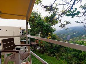 a balcony with a chair and a view of the mountains at Cabaña tipi Ardilla Silvania Cundinamarca in Silvania +3 photos