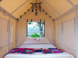 a bed in a small room with a window at Cabaña tipi Ardilla Silvania Cundinamarca in Silvania